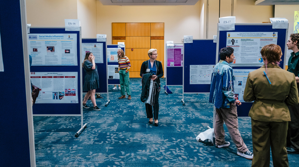 Several undergraduate students investigate posters submitted to research expo